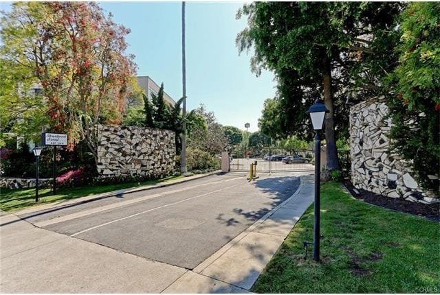 view of street featuring street lighting, a gate, a gated entry, and curbs