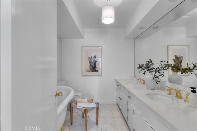 bathroom with a freestanding bath, baseboards, a sink, and double vanity