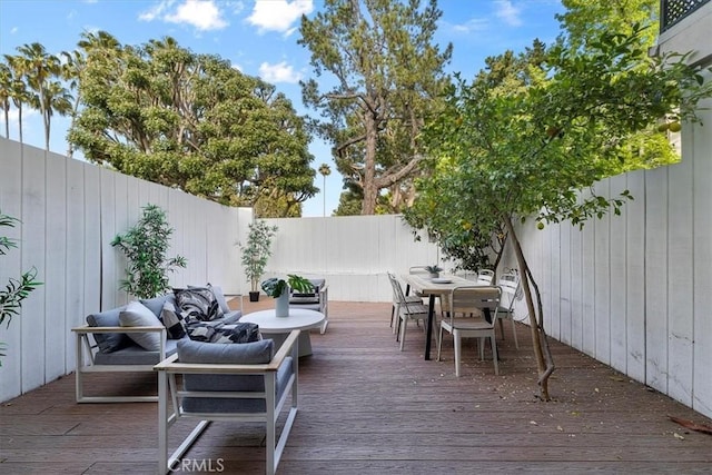wooden terrace with a fenced backyard and outdoor dining space