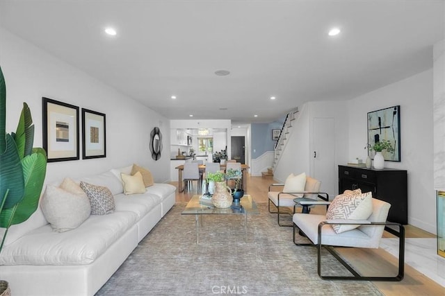 living room with recessed lighting, light wood-type flooring, and stairs
