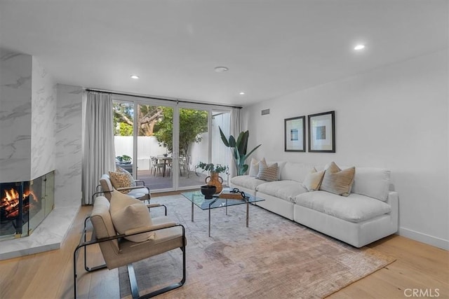 living area with recessed lighting, wood finished floors, a fireplace, and baseboards