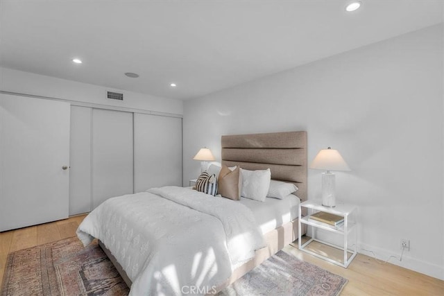 bedroom featuring wood finished floors, visible vents, recessed lighting, and a closet