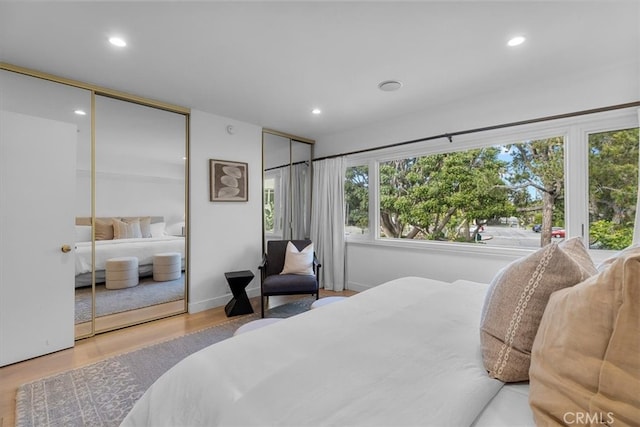 bedroom featuring multiple closets, wood finished floors, and recessed lighting