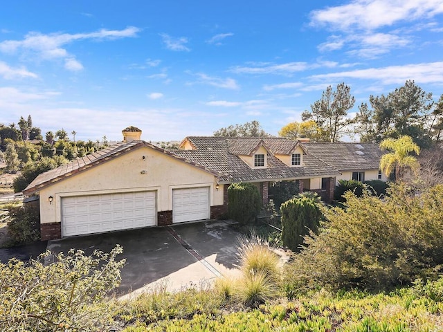 view of front facade with an attached garage, stucco siding, concrete driveway, and brick siding