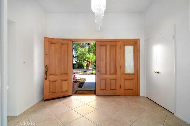 tiled entryway with a chandelier