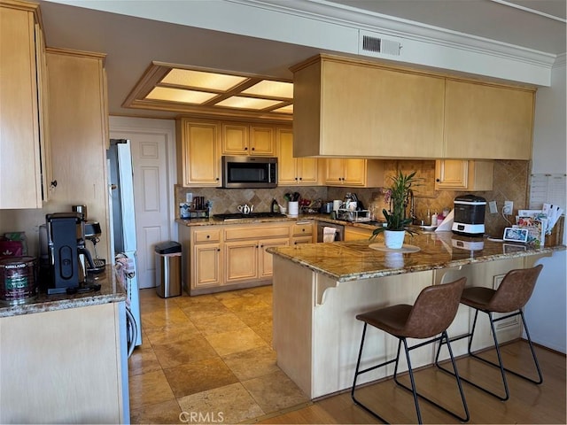 kitchen featuring stone countertops, light brown cabinetry, kitchen peninsula, and appliances with stainless steel finishes