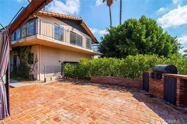 view of home's exterior featuring a patio, a balcony, and exterior kitchen