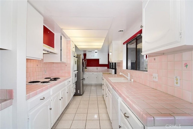 kitchen with white cabinetry, sink, white appliances, and tile counters