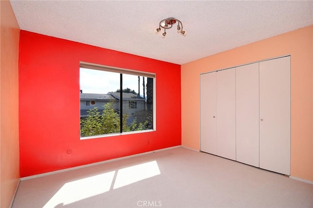 unfurnished bedroom with a closet, light carpet, and a textured ceiling