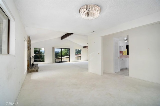 empty room with a notable chandelier, a textured ceiling, and vaulted ceiling with beams