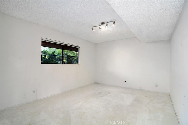 spare room featuring light carpet and a textured ceiling