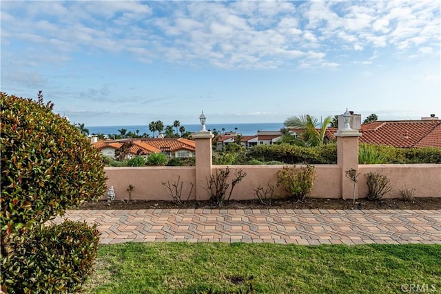 view of patio featuring a water view and fence