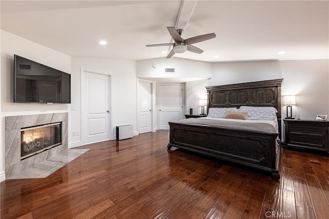 bedroom with recessed lighting, dark wood-style flooring, visible vents, a high end fireplace, and vaulted ceiling