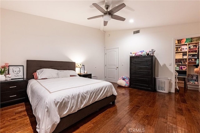 bedroom featuring a walk in closet, a closet, visible vents, dark wood-type flooring, and ceiling fan