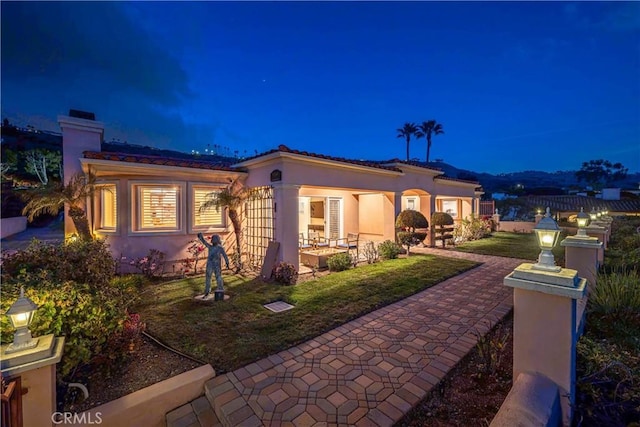 mediterranean / spanish home featuring a patio, a yard, a chimney, stucco siding, and fence