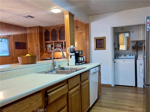 kitchen featuring sink, light hardwood / wood-style flooring, dishwasher, independent washer and dryer, and a textured ceiling