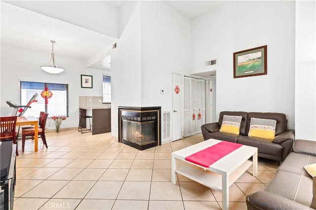 tiled living room featuring a multi sided fireplace and a towering ceiling