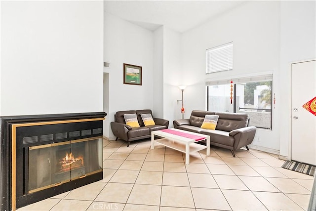 tiled living room featuring a towering ceiling and a multi sided fireplace