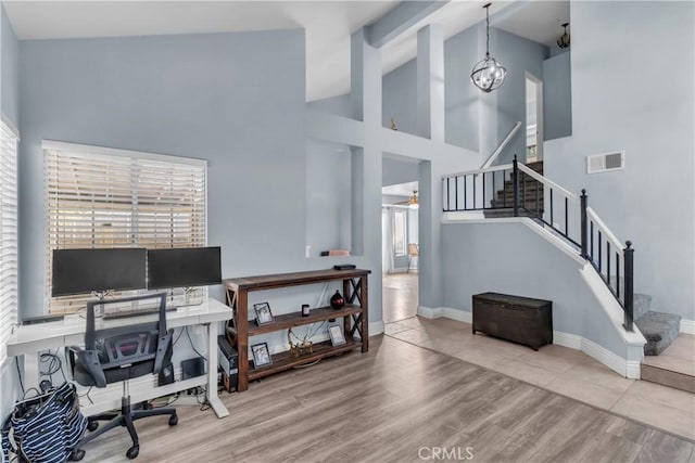 home office featuring ceiling fan with notable chandelier, high vaulted ceiling, and light hardwood / wood-style flooring