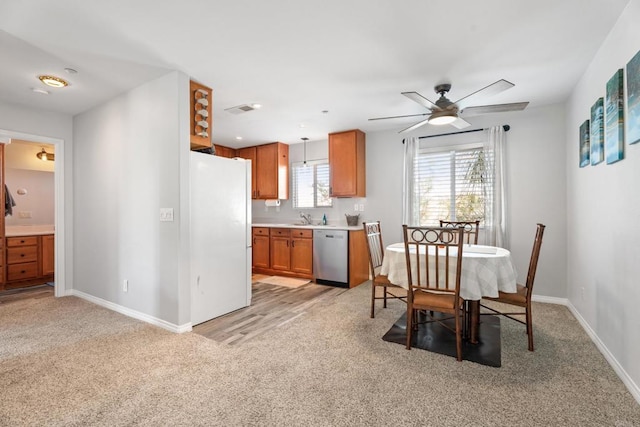 dining space with ceiling fan, light colored carpet, and sink