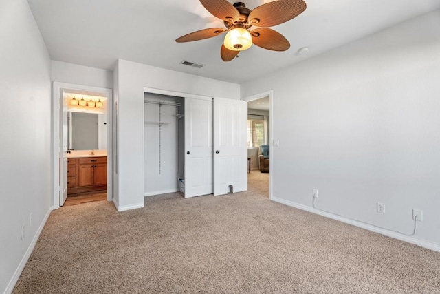 unfurnished bedroom featuring connected bathroom, light colored carpet, a closet, and ceiling fan