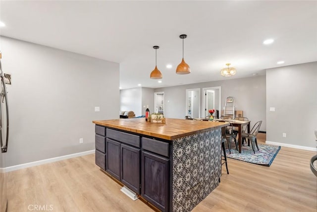 kitchen with wood counters, decorative light fixtures, a kitchen island, and light wood-type flooring