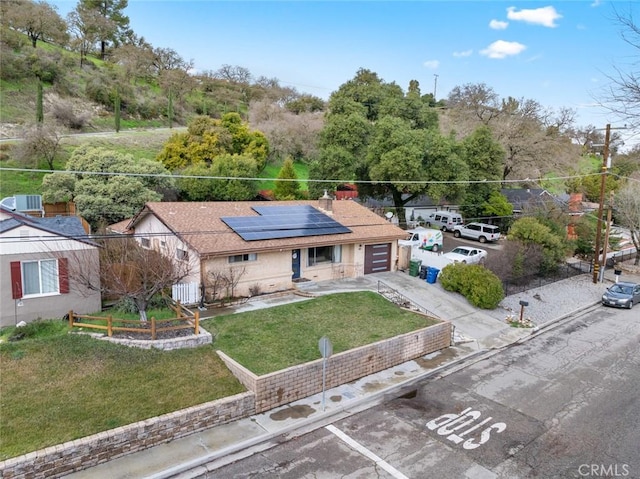 view of front of home with a garage, a front lawn, and solar panels