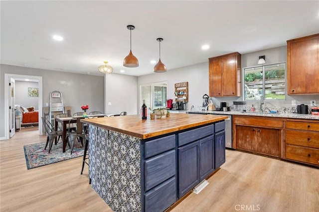 kitchen with a center island, sink, pendant lighting, and light wood-type flooring