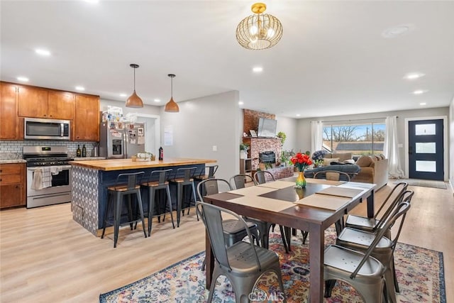 dining space featuring light wood-style floors, recessed lighting, and a fireplace