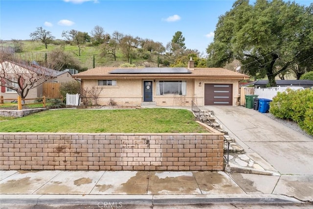 ranch-style home with a garage, a front yard, and solar panels