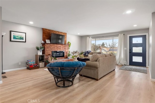 living room featuring a brick fireplace and light hardwood / wood-style floors