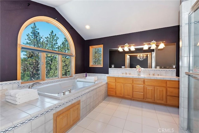 bathroom featuring lofted ceiling, vanity, tile patterned flooring, and tiled tub