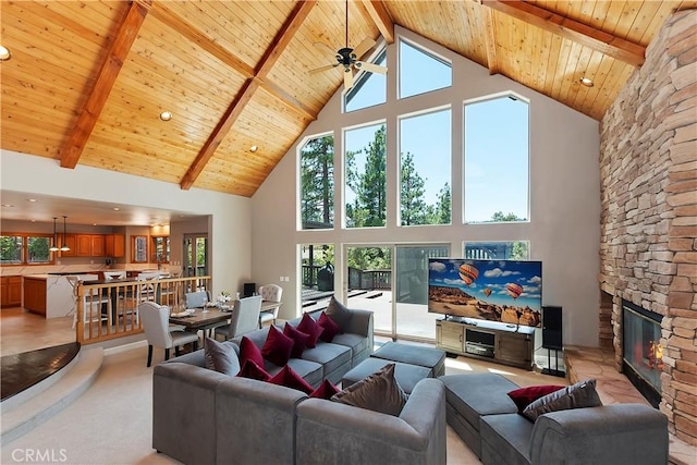 living room featuring wood ceiling, plenty of natural light, a stone fireplace, and beam ceiling