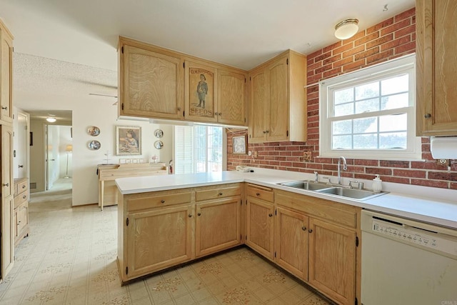 kitchen featuring brick wall, sink, white dishwasher, and kitchen peninsula