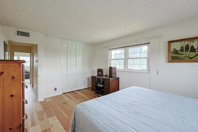 bedroom featuring a closet, a textured ceiling, and light wood-type flooring