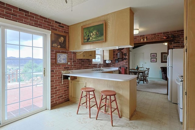 kitchen featuring a kitchen bar, a textured ceiling, brick wall, a mountain view, and kitchen peninsula