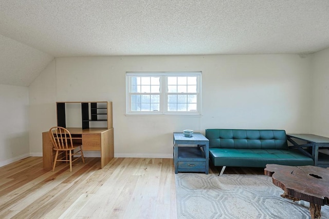 sitting room featuring wood-type flooring, vaulted ceiling, and a textured ceiling