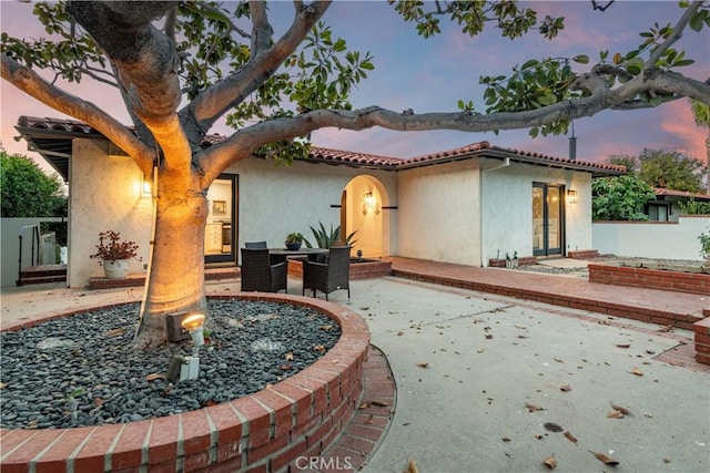 back house at dusk with a patio area