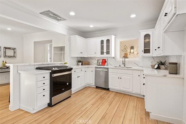 kitchen featuring appliances with stainless steel finishes, white cabinetry, sink, ornamental molding, and light hardwood / wood-style flooring