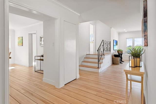 hall with ornamental molding and light hardwood / wood-style floors