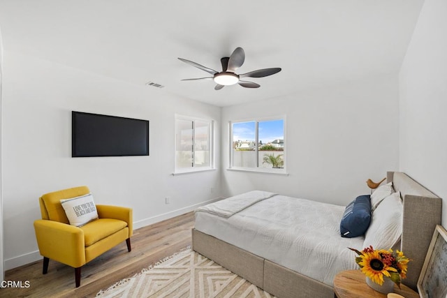 bedroom featuring light wood-style flooring, a ceiling fan, visible vents, and baseboards