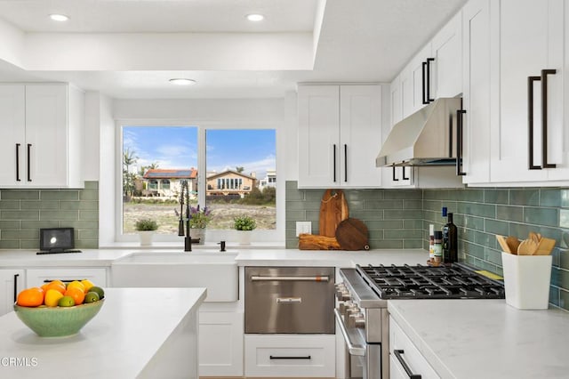 kitchen with stainless steel range, a sink, white cabinets, and under cabinet range hood