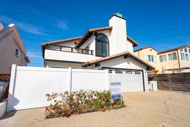 view of front of home with concrete driveway, a tile roof, a chimney, fence, and stucco siding