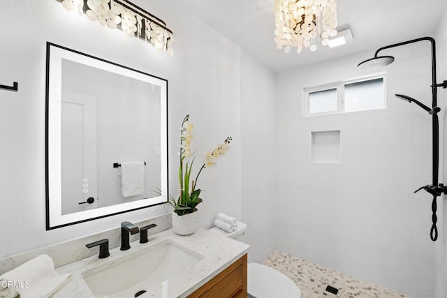 bathroom with tiled shower, vanity, toilet, and an inviting chandelier