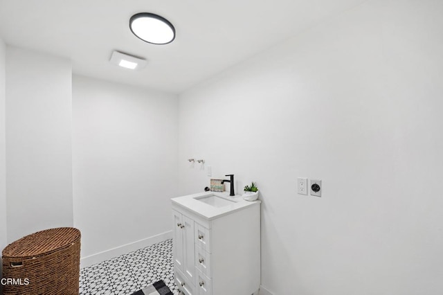 clothes washing area with light floors, hookup for an electric dryer, a sink, and baseboards