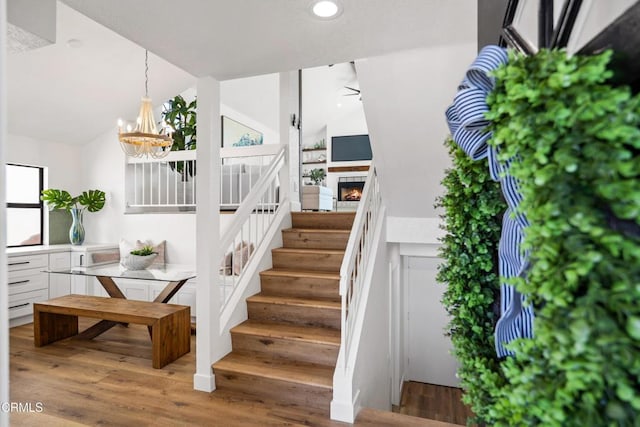 stairway featuring lofted ceiling, ceiling fan with notable chandelier, wood finished floors, and recessed lighting