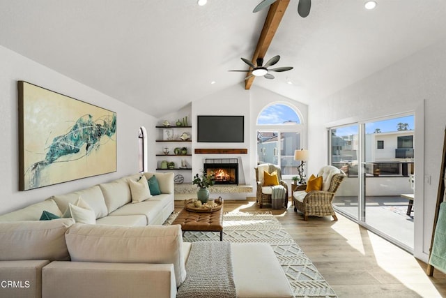 living area with recessed lighting, high vaulted ceiling, light wood-type flooring, a warm lit fireplace, and beamed ceiling