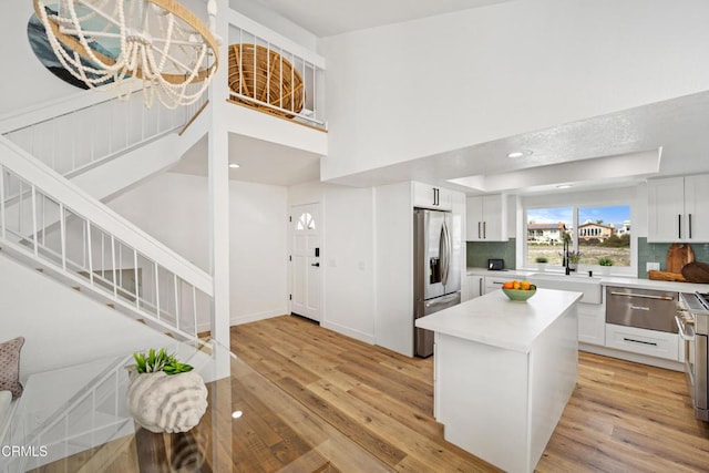 kitchen featuring a center island, light countertops, light wood-style floors, white cabinets, and stainless steel fridge with ice dispenser