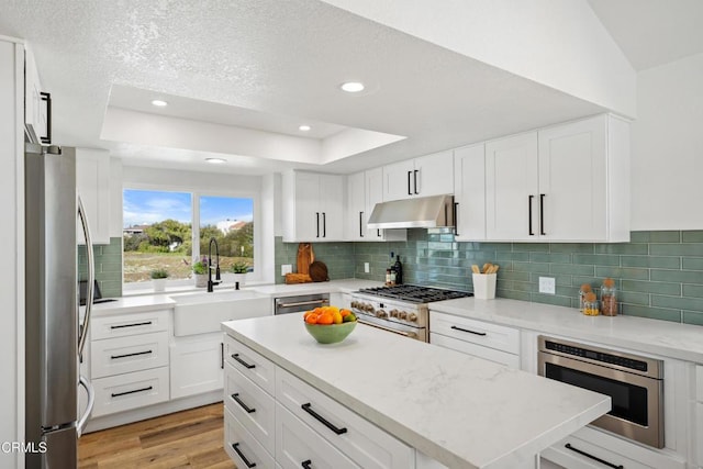 kitchen featuring appliances with stainless steel finishes, a sink, white cabinetry, and under cabinet range hood