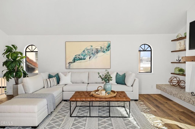 living room featuring lofted ceiling, wood finished floors, and baseboards